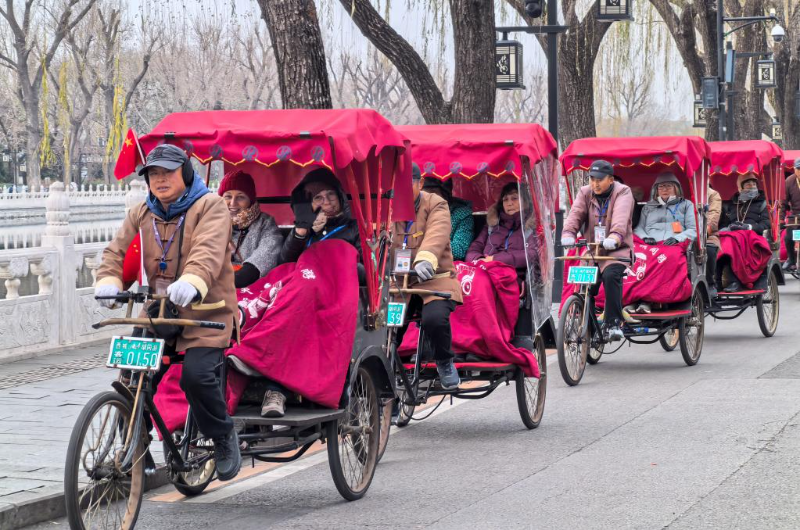 2024年12月12日，外國游客在北京什剎海乘坐人力三輪車觀光。新華社記者 鞠煥宗 攝